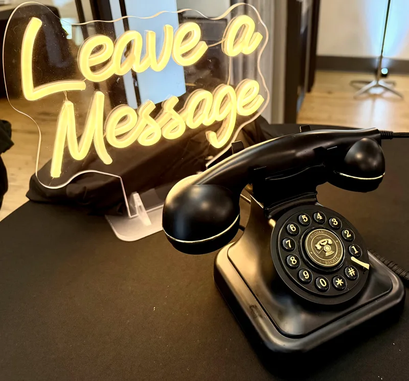 Audio guest book rental, a vintage black telephone with a Leave a Message neon sign at a SwissMixx Audio wedding reception