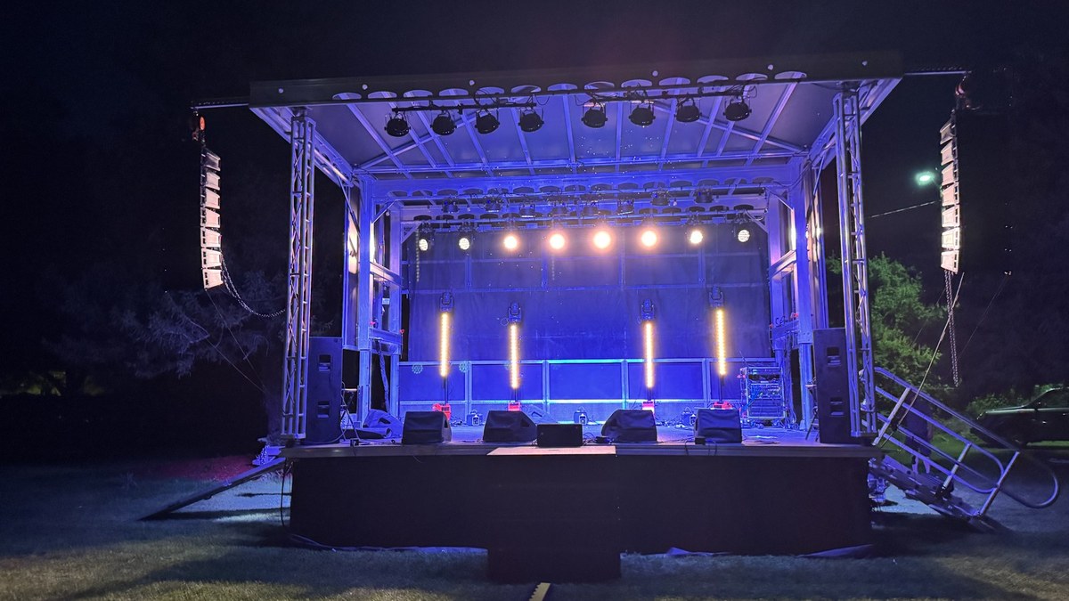 An empty SwissMixx festival stage at night, line array speakers flown on both sides of the lighting truss, ready before doors