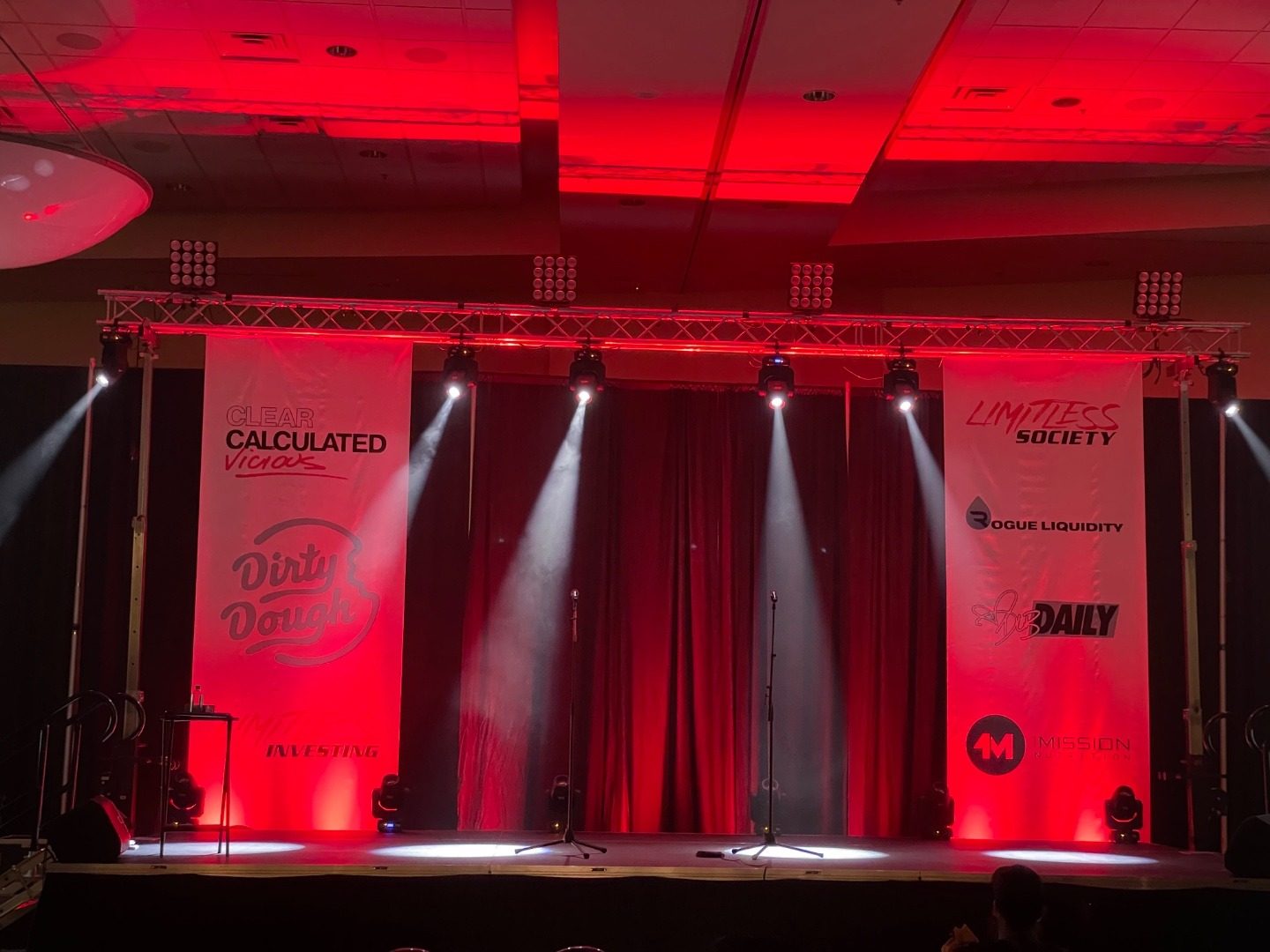Corporate event stage with professional red lighting and sponsor banners