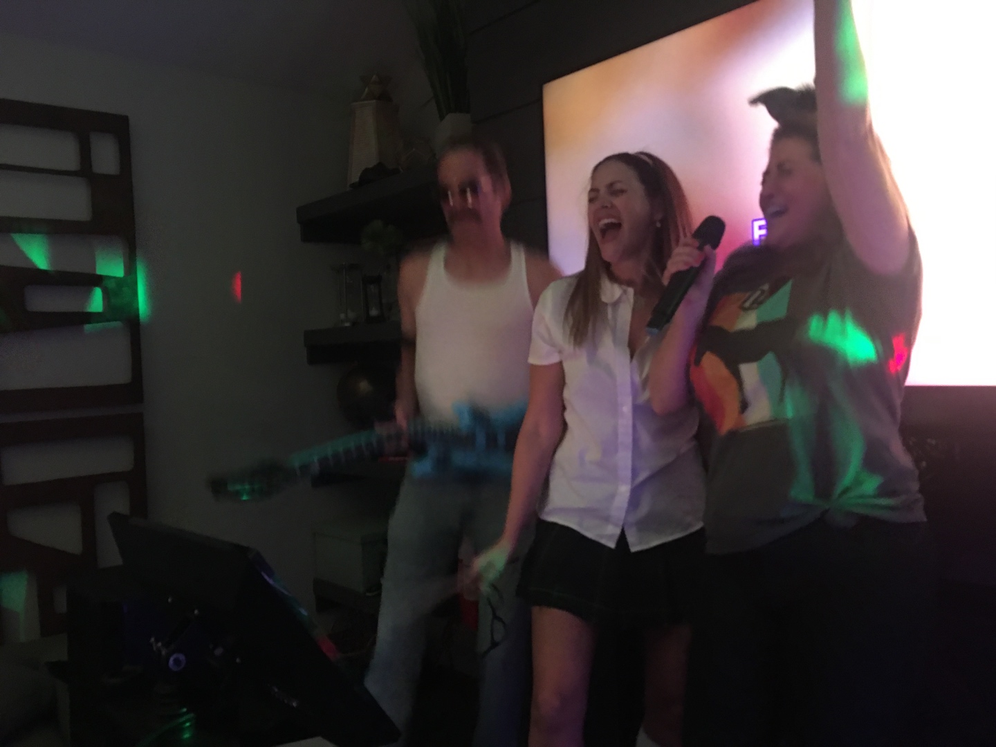 Three guests laughing and singing at a private karaoke party with colorful lighting, SwissMixx Audio