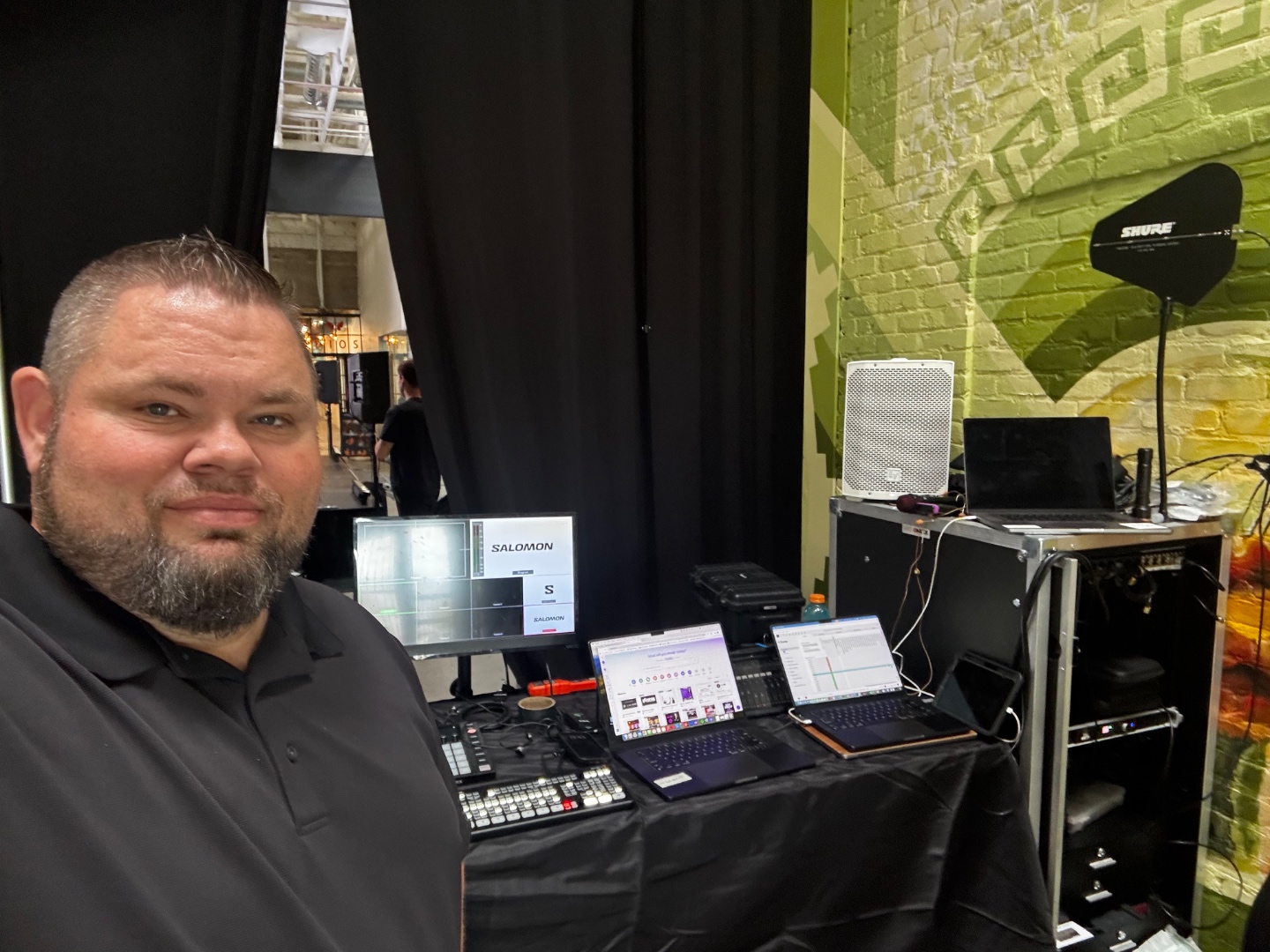 Mark Christiansen backstage at Salomon corporate event managing AV control with video switcher, audio software, and Shure RF system