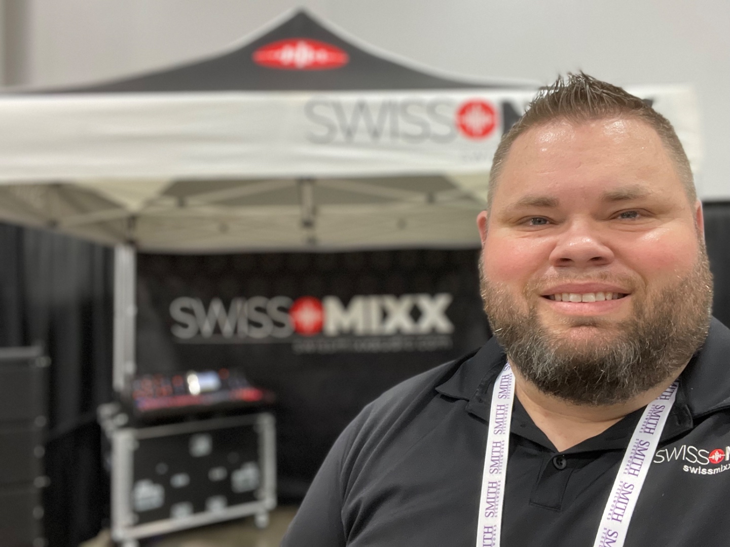 Mark Christiansen at the SwissMixx Audio convention booth with branded banner and tent at a trade show or expo event