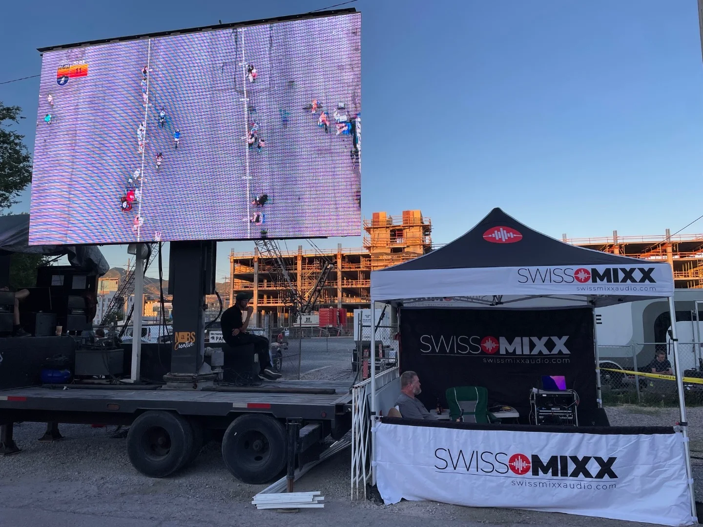SwissMixx Audio LED video wall showing a live race feed beside the SwissMixx tent and audio booth at a criterium
