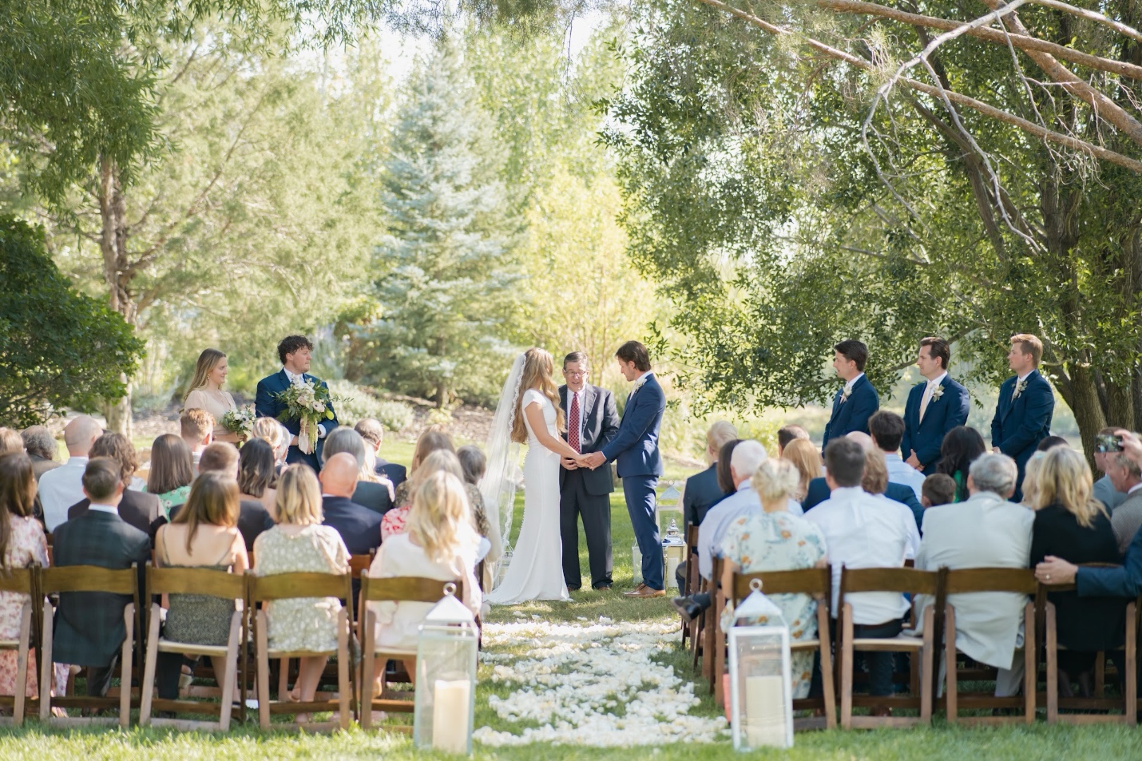 Outdoor wedding ceremony in Idaho with bride and groom under lush trees, professionally sound reinforced by SwissMixx Audio