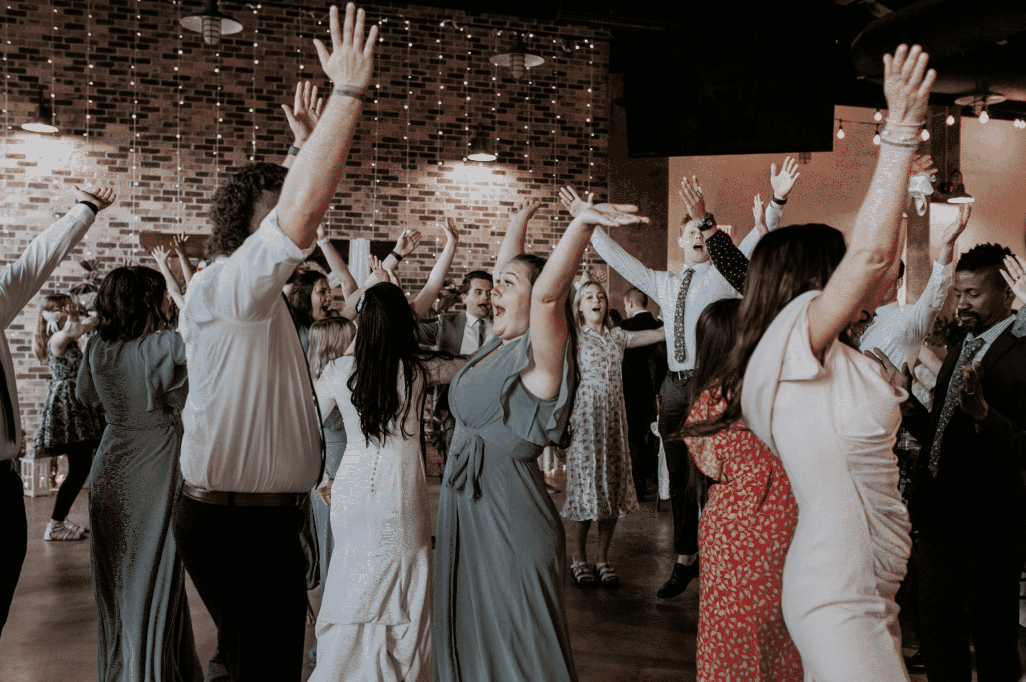 Wedding guests dancing with hands raised at Boise Idaho reception, professional sound by SwissMixx Audio